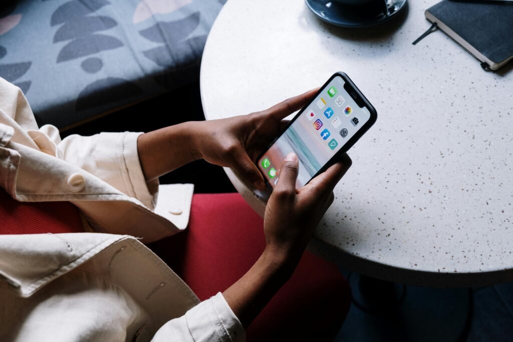 A person checks social media apps on a smartphone while sitting at a café table.